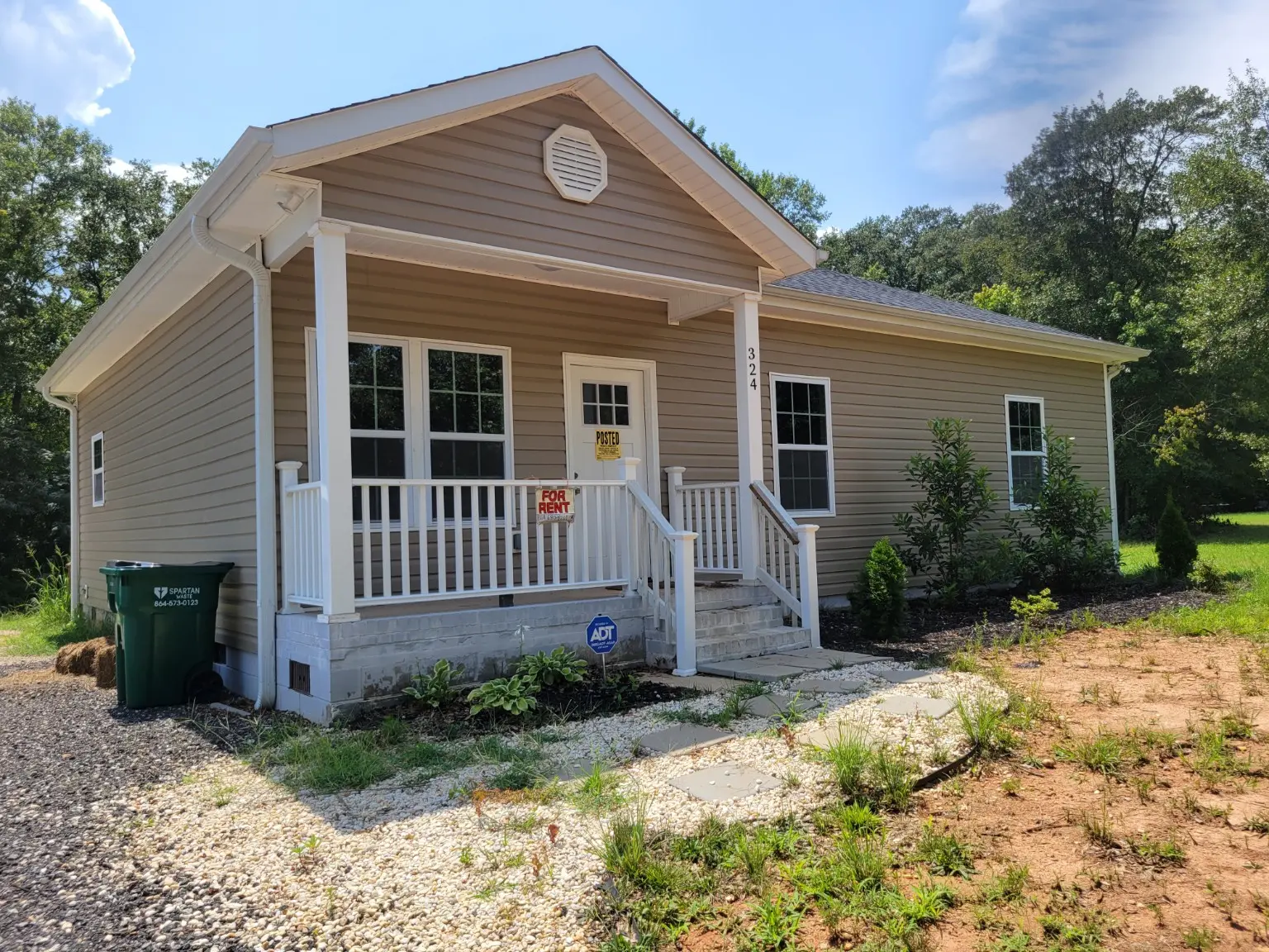 Front exterior of 324 Great Oak Drive showing tan siding, a covered front porch with white railings, and front steps at 324 Great Oak Drive