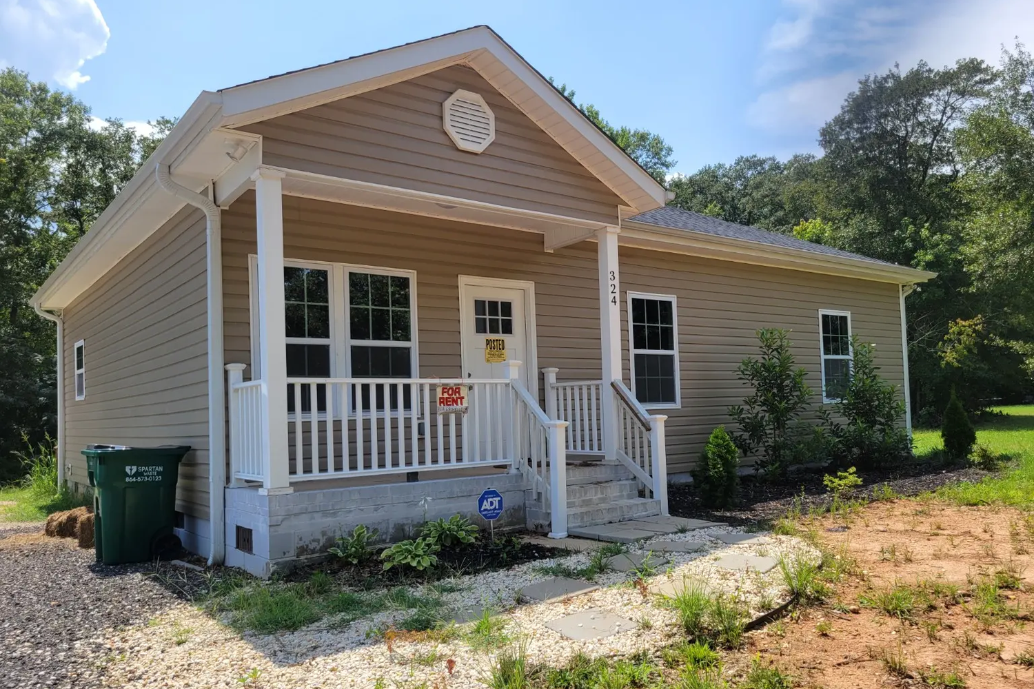 Front exterior of 324 Great Oak Drive showing tan siding, a covered front porch with white railings, and front steps at 324 Great Oak Drive